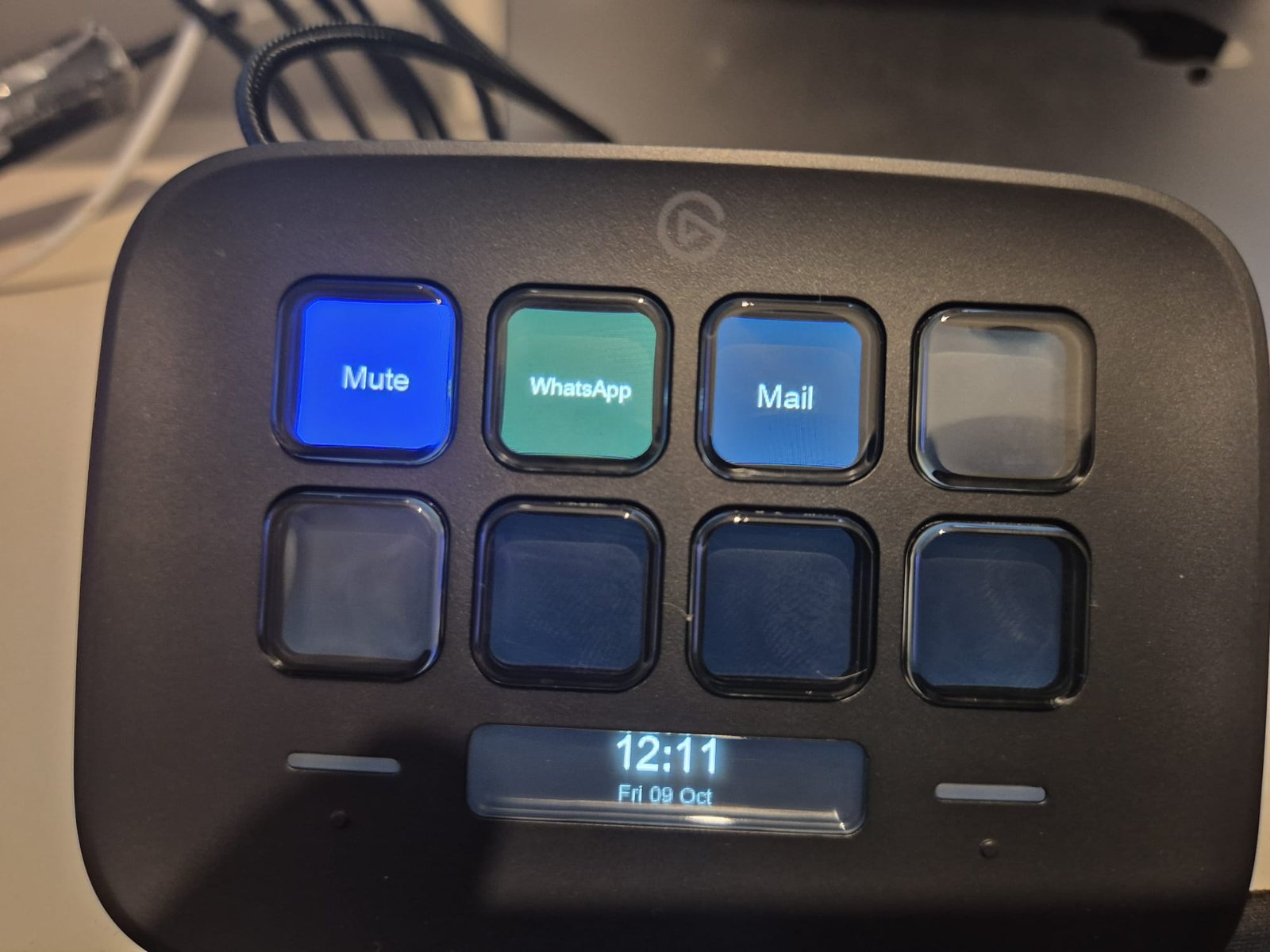A Stream Deck Neo on a desk showing three text keys labelled Mute, WhatsApp and Mail, and a clock on its display.